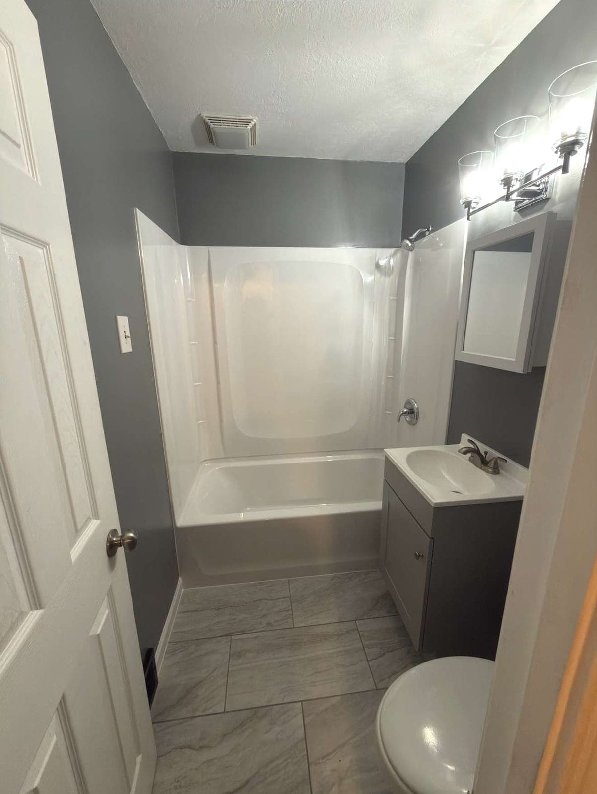 Remodeled bathroom with a new tub surround and large-format tile floor