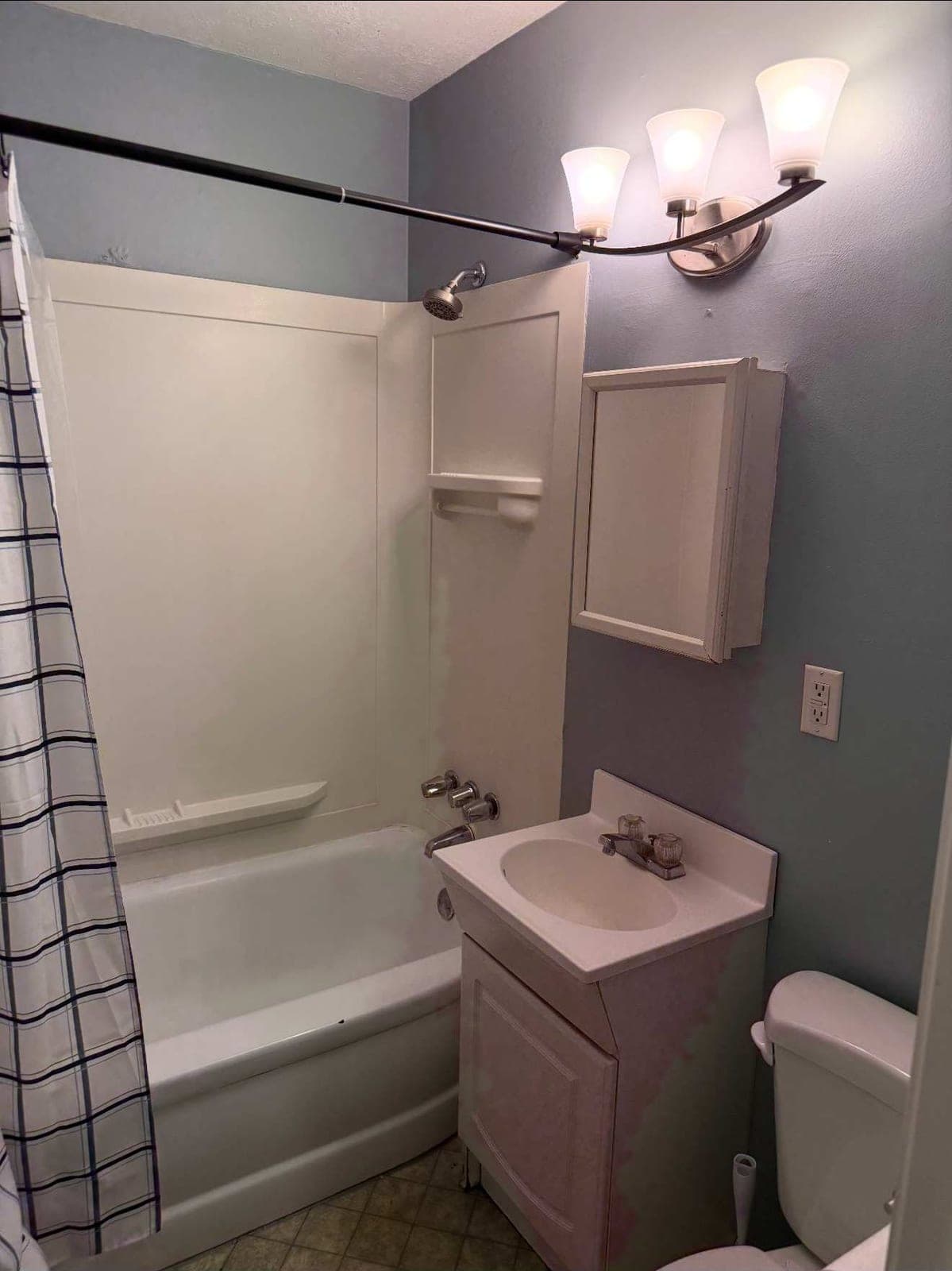 Bathroom before remodel with old tub, vanity and vinyl floor